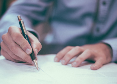 Main signant un document avec un stylo